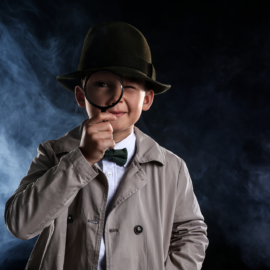 Niño disfrazado de detective con lupa y sombrero, representación del estereotipo clásico del detective privado