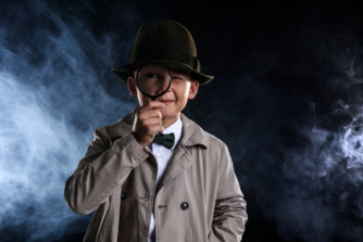 Niño disfrazado de detective con lupa y sombrero, representación del estereotipo clásico del detective privado