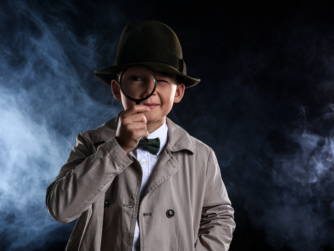 Niño disfrazado de detective con lupa y sombrero, representación del estereotipo clásico del detective privado