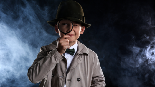 Niño disfrazado de detective con lupa y sombrero, representación del estereotipo clásico del detective privado