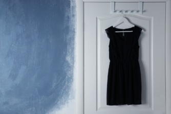 Vestido negro colgado en una puerta esperando una noche de vigilancia