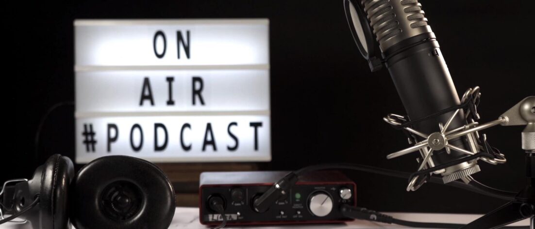 Micrófono y equipo de grabación de podcast en estudio con cartel luminoso “On Air Podcast”