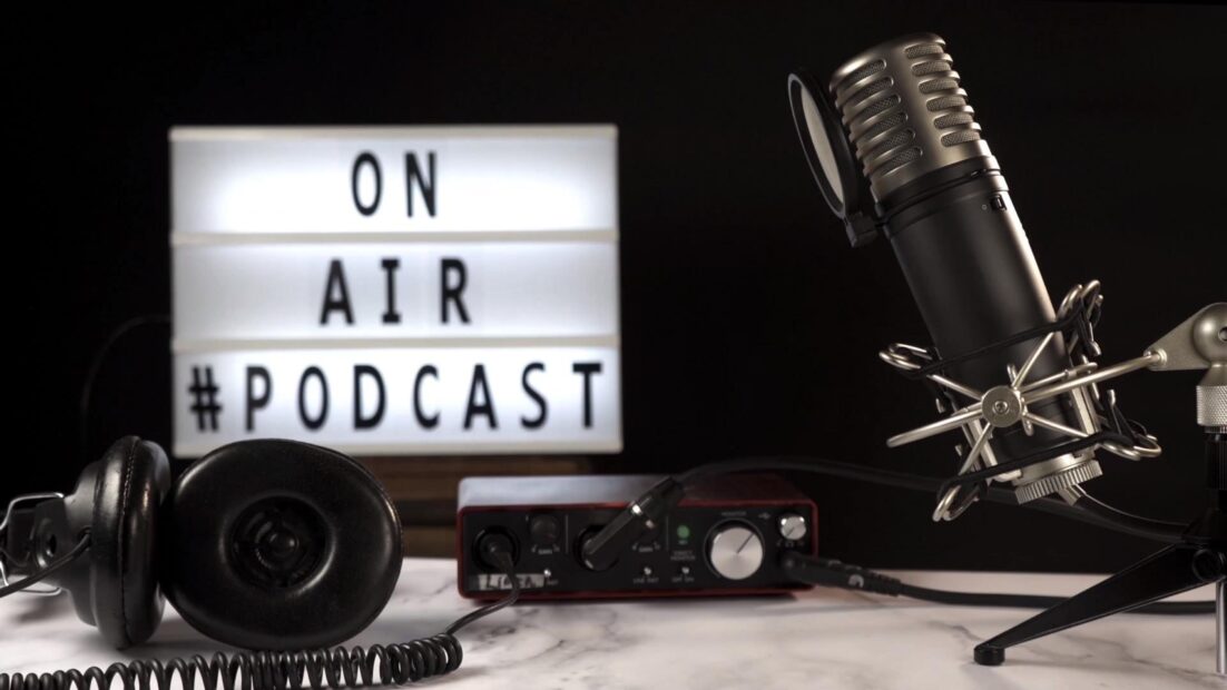 Micrófono y equipo de grabación de podcast en estudio con cartel luminoso “On Air Podcast”