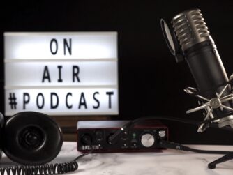 Micrófono y equipo de grabación de podcast en estudio con cartel luminoso “On Air Podcast”